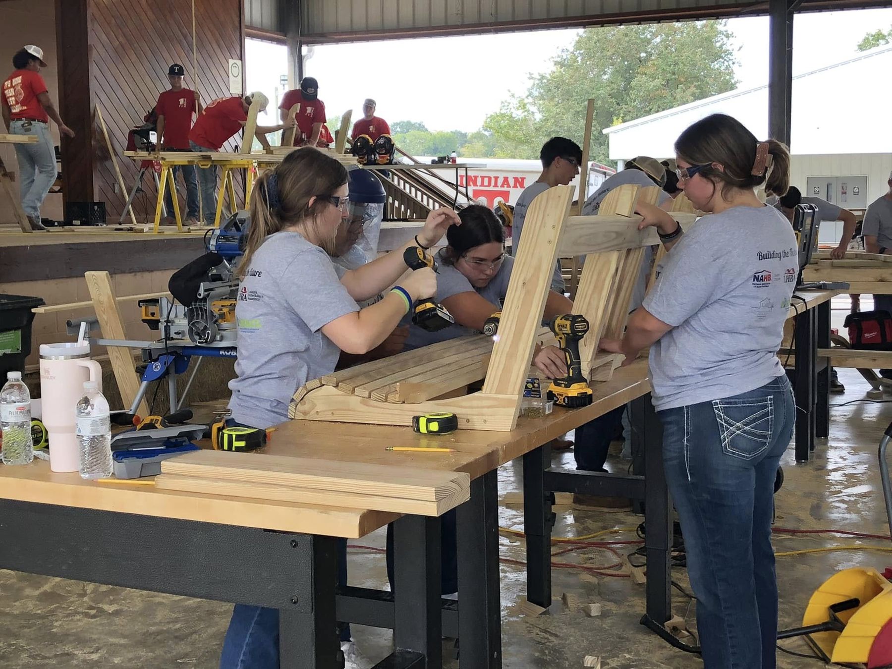 Students building wooden workbenches side by side at a hands-on trades event