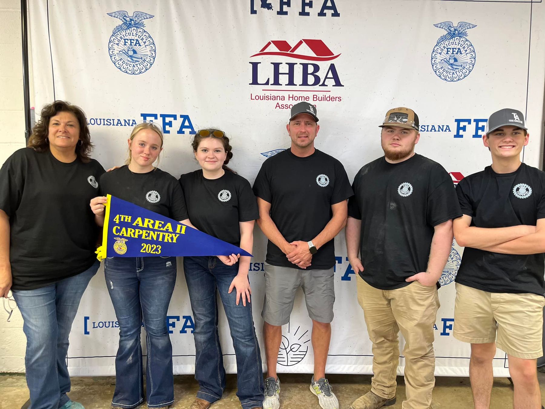 Students and advisors holding a carpentry pennant in front of a Louisiana FFA backdrop