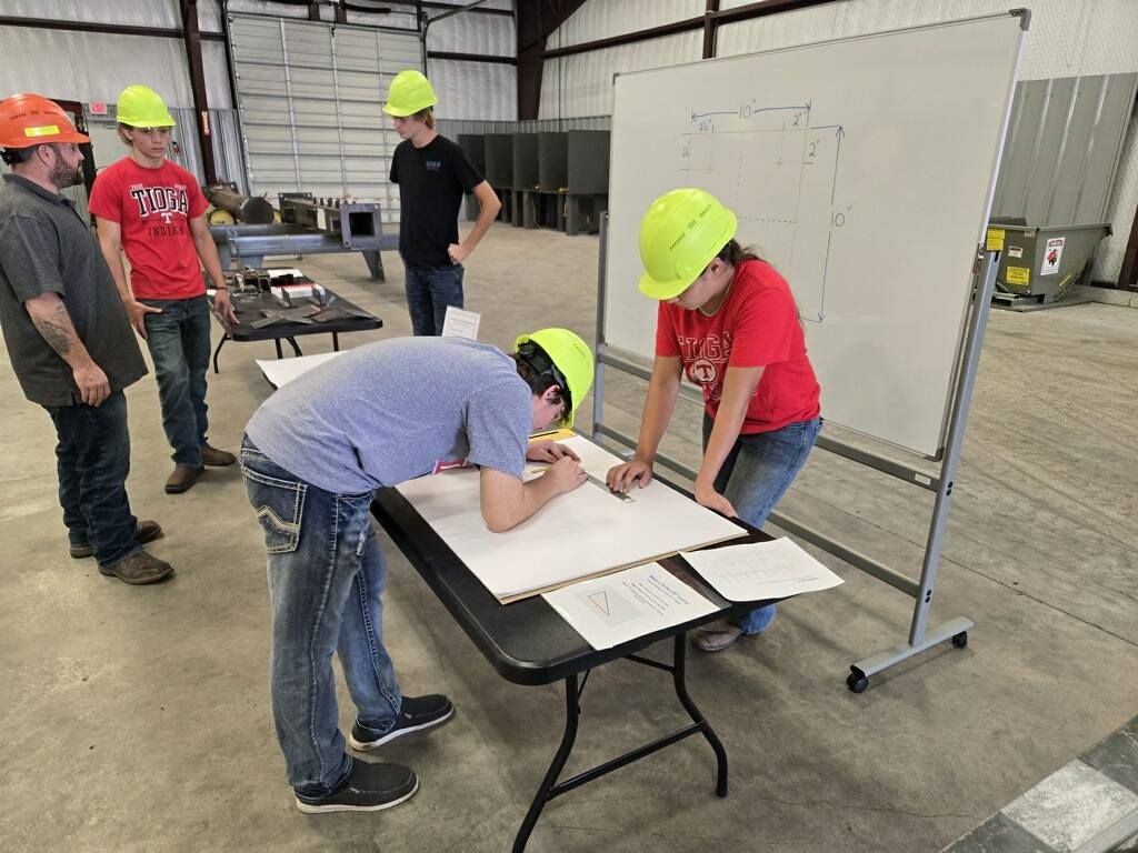 Students in hard hats working over blueprints at a trades event