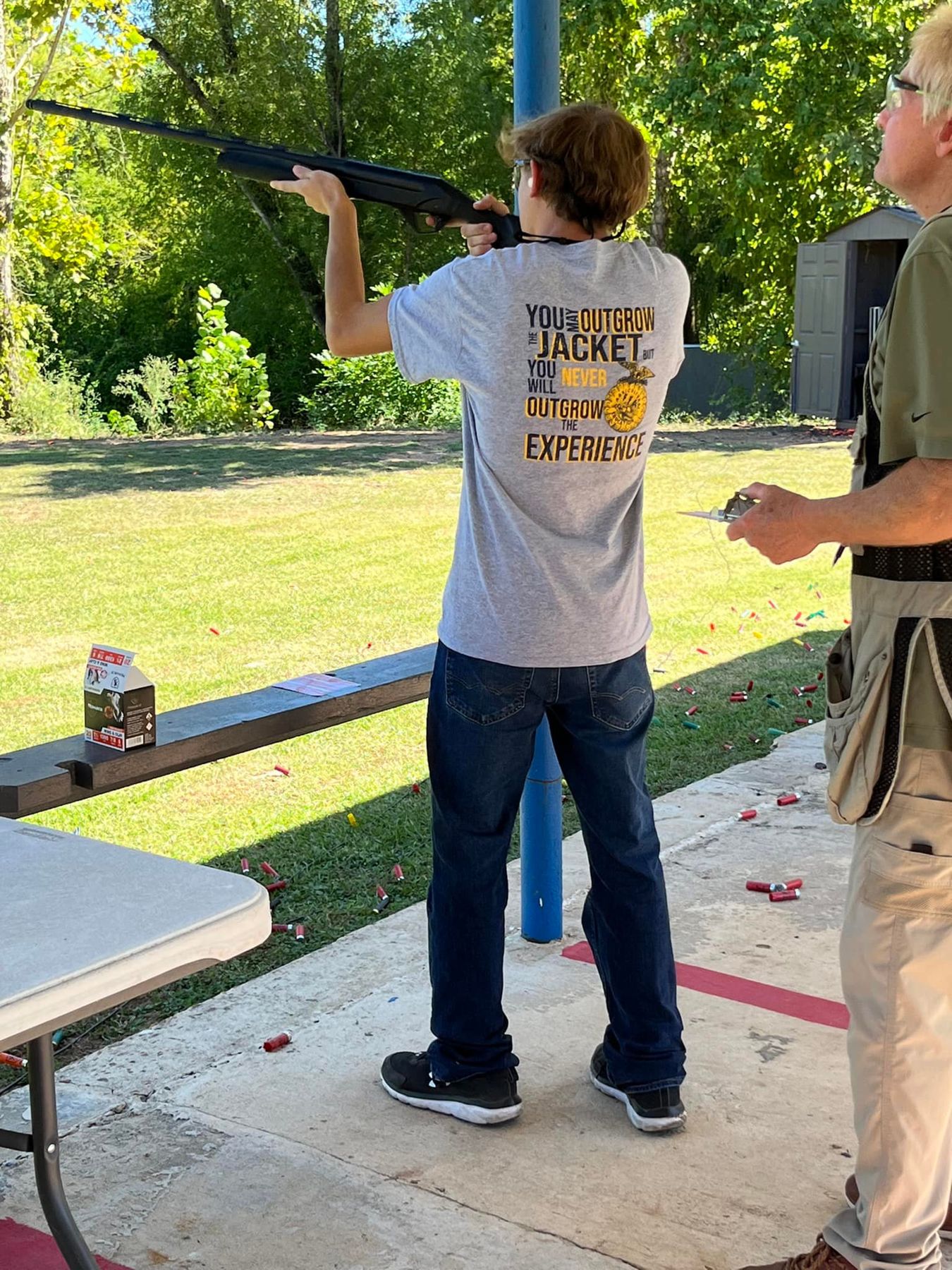 Student at a skeet shooting event with a range officer